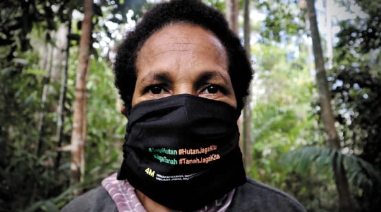 Papuan woman wearing a mask with the slogan “Protect the forest – the forest protects us”