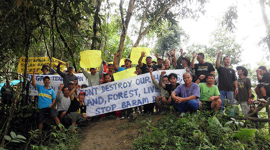Indigenous peoples of the Sarawak rainforest protesting with banners against Baram Dam