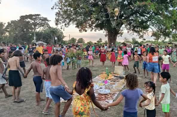 Dozens of people – women, men, children and elders – form a circle around an offering of food, seeds and other gifts of the earth laid out on the ground
