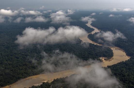 Aerial view of a river meandering through a rainforest, clouds