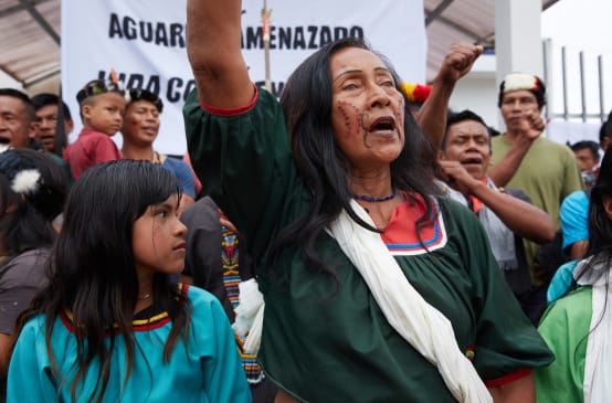 Indigenous people protesting, a banner in the background