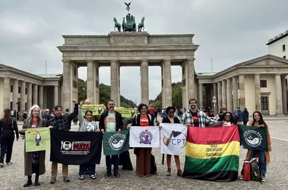 A group of 11 people holding banners in front of the Brandenburg Gate in Berlin