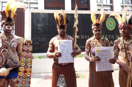 four Papuans in traditional dress in front of the courthouse