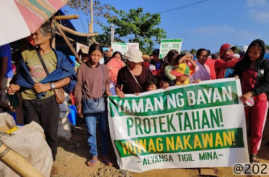 A group of people holding a banner that reads (translated): “Protect the wealth of the people! Stop the theft! Alliance Against Mining”