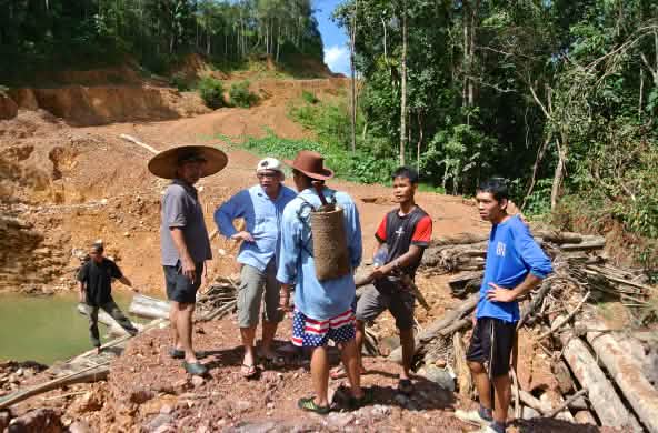Indigenous people stand on a dirt road illegally built by loggers in Sarawak