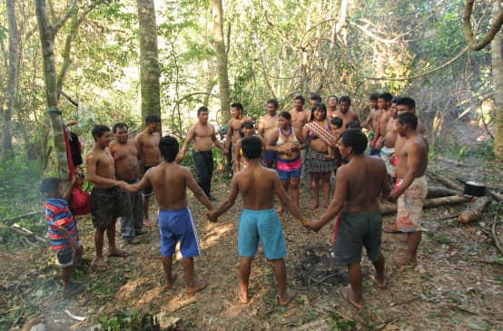 Indigenous Ka'apor people – children, women and men – join hands and form a circle in the rainforest