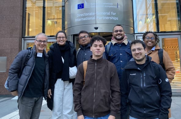 Group photo of seven people in front of the entrance of a building of the EU Commission in Brussels