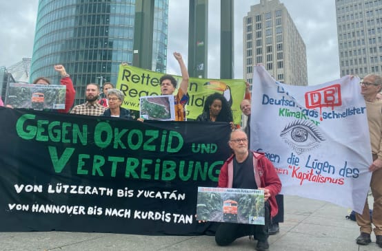 A group of people protesting with large, colorful banners in front of three office buildings