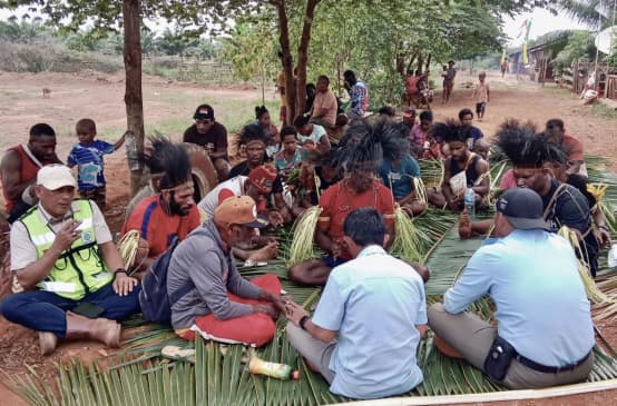 A group of Papuans sitting on palm leaves