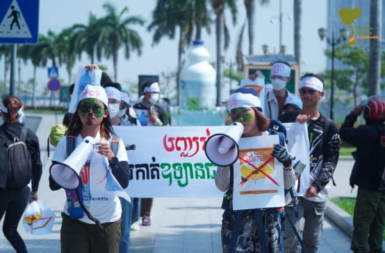 A group of young students walks through a street with megaphones and banners