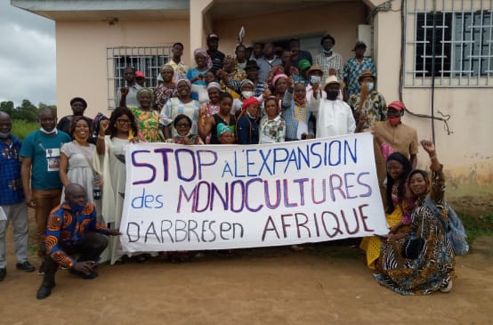 A group of people holding a banner opposing tree plantations
