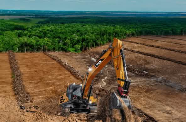 Excavator on deforested land – the forest in the background is threatened