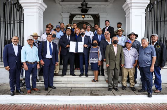 A group of around 20 people, with the President of Panama in the center of the picture, present the signed law at the entrance to the presidential palace