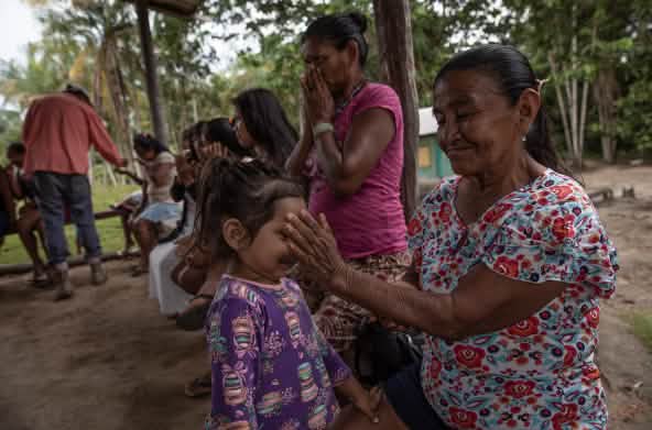 A young girl smells the essential oils in an Indigenous woman’s hand