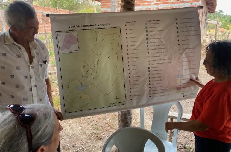 Three people looking at a map hanging on a wooden post