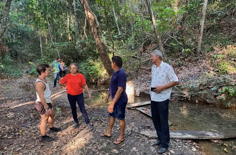 A group of people standing at a water source in the rainforest