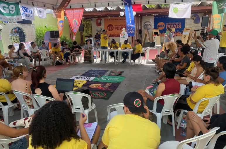 Around 30 people in a circle sitting on chairs in a meeting room