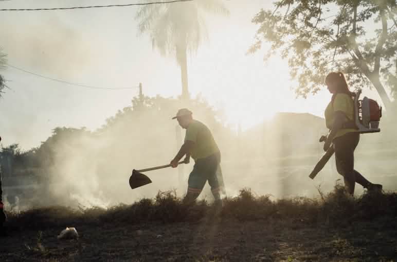 A man with a fire beater and a woman with a portable blower during an exercise, backlit