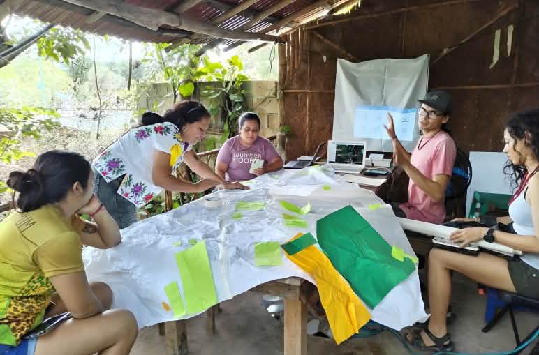Five women around a table working on materials