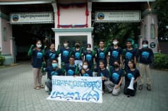 A group of 15 young people standing and kneeling in front of the Ministry of Tourism building, holding a banner to the camera. It reads “Koh Kong Island must become a marine national park”
