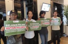 Four men hold placards reading “Save the forest and livelihoods of the people of Loeha Raya”