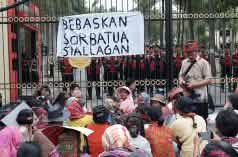Protest in front of high fence with banner “Free Sorbatua Siallagan”