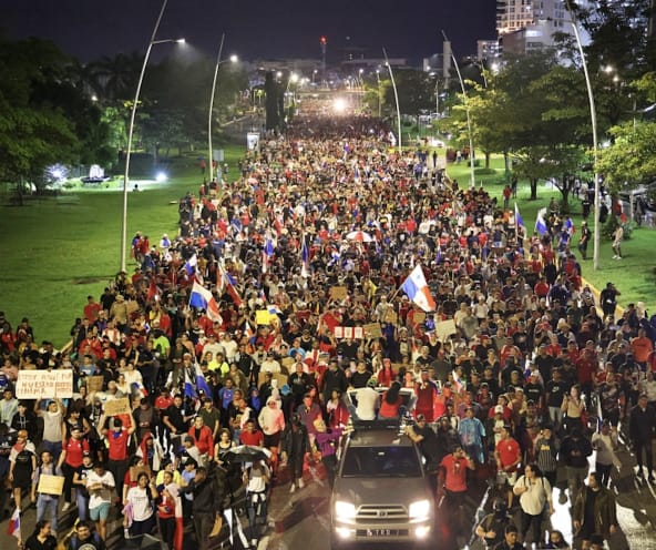 A protest march with thousands of people fills a street in the capital