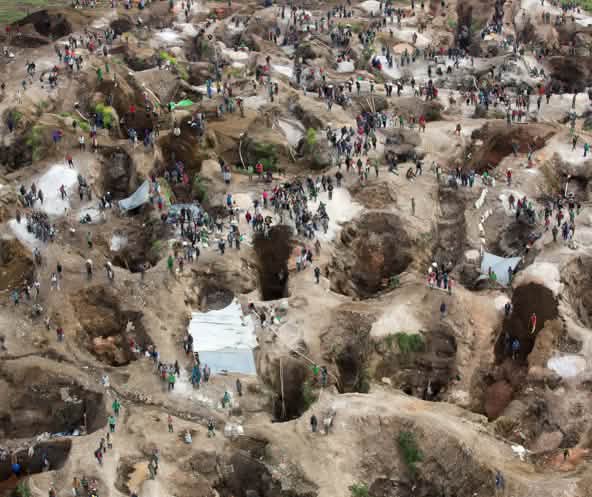 Deep holes, some filled with water, with many people in between. View from above
