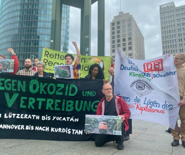 A group of people protesting with large, colorful banners in front of three office buildings