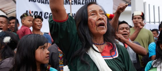 Indigenous people protesting, a banner in the background