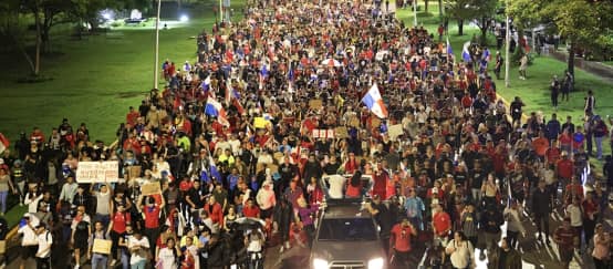 A protest march with thousands of people fills a street in the capital