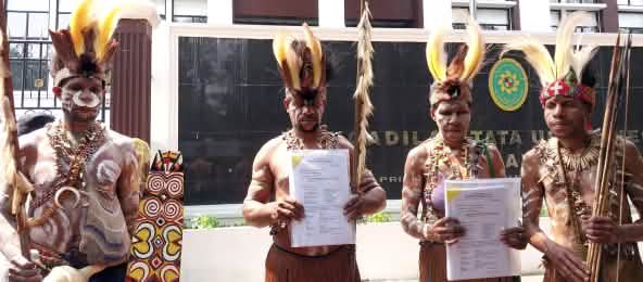 Indigenous Papuans: “We are going to appeal! This case will decide the future of the forest in southern Papua.” (© Pusaka) four Papuans in traditional dress in front of the courthouse