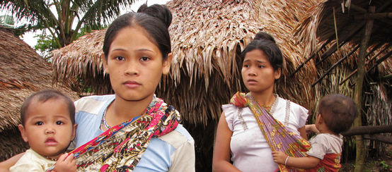 Two women with their children in front of thatched houses