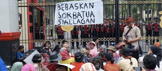 Protest in front of high fence with banner “Free Sorbatua Siallagan”