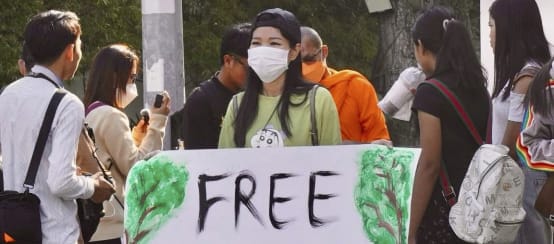 Young woman holding a large placard with the text “Free Mother Nature Activist!”