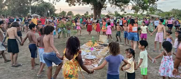 Dozens of people – women, men, children and elders – form a circle around an offering of food, seeds and other gifts of the earth laid out on the ground