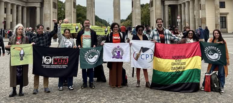 A group of 11 people holding banners in front of the Brandenburg Gate in Berlin
