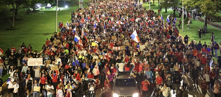 A protest march with thousands of people fills a street in the capital