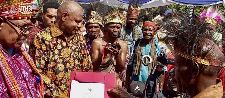A group of Papuans in traditional clothing holding a certificate