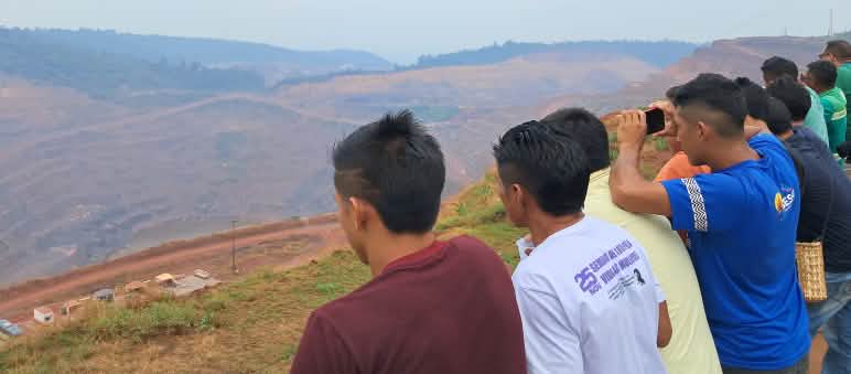 More than ten people observe the destruction caused by mining activities at the edge of a Vale iron ore mine