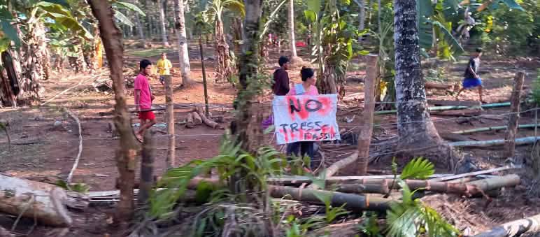 People in the coconut plantation with a banner that says "no trespassing"