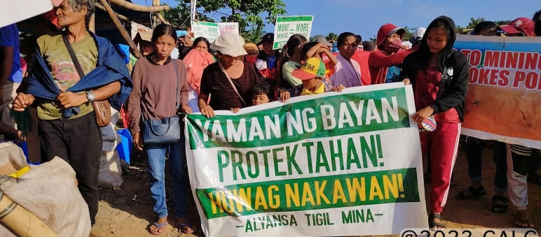 Banner: “Protect the wealth of the people! Stop the theft! Alliance Against Mining” A group of people holding a banner that reads (translated): “Protect the wealth of the people! Stop the theft! Alliance Against Mining”