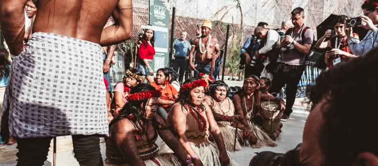 Indigenous women sit on the ground to block the entrance to COP30 in Belém