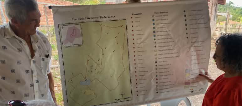 Three people looking at a map hanging on a wooden post