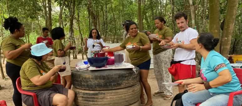 A group of nine people having lunch and chatting around an improvised table
