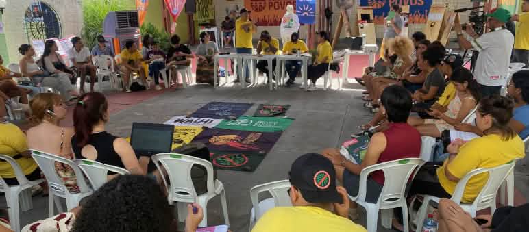 Around 30 people in a circle sitting on chairs in a meeting room