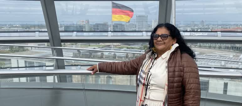 Quilombola woman Marli Borges in the glass dome of the German Bundestag, with the German flag in the background