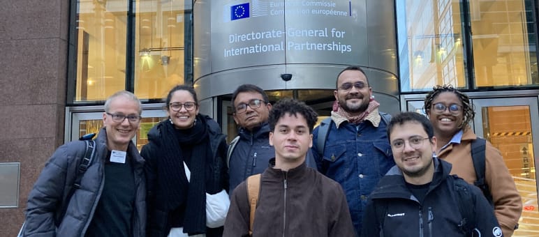 Group photo of seven people in front of the entrance of a building of the EU Commission in Brussels