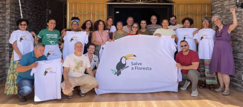 Group photo of 20 people with a banner and T-shirts bearing the organization's toucan logo and the slogan Salve a Floresta (Rainforest Rescue)