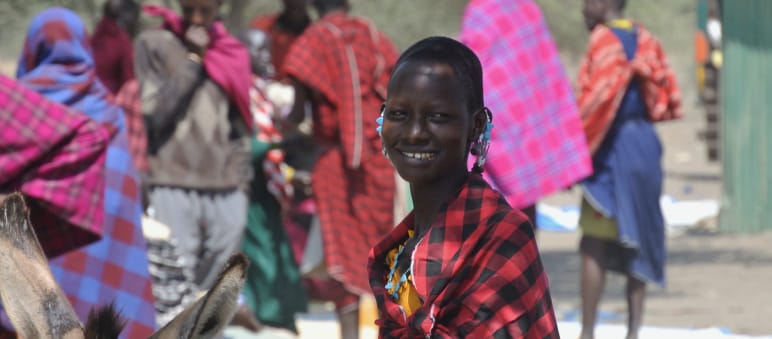 Maasai people at a market near Ngorongoro Crater Maasai women and men in colorful cloths at a market, a woman looks at the camera